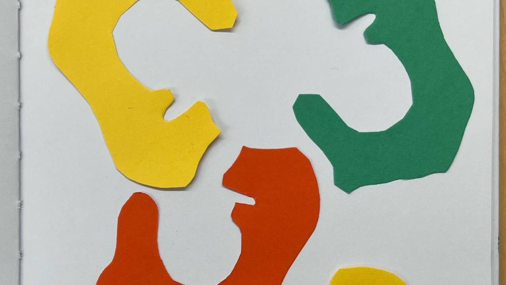 A collage of abstract splotch shapes cut from yellow, orange, red, and green paper arranged on a white background.