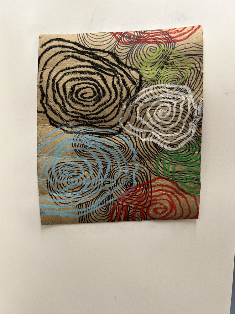 A mixed media artwork featuring a series of swirling spiral lines in black ink over a brown paper background. Several spirals are highlighted in bright colors, including red, blue, green, and white, creating an abstract, layered effect.
